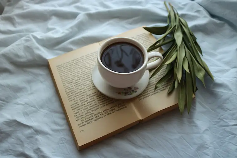 cup of coffee on top of open book background